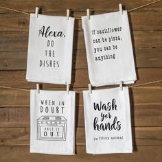 four tea towels hanging on clothes pins with handwritten sayings in black and white