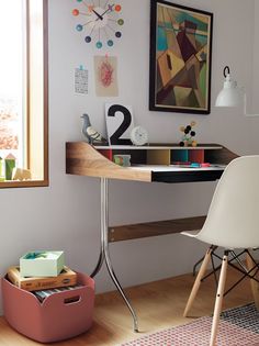 a desk and chair in a room with a painting on the wall behind it next to a window