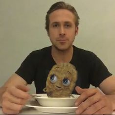 a man sitting at a table with a plate and bowl in front of his face