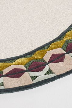 a close up of a rug on the floor with an oval design in gold, red and green