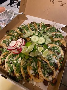 an open box filled with tacos and veggies on top of a counter