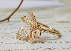 a gold leaf ring sitting on top of a piece of paper