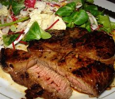 a white plate topped with steak, salad and lettuce on top of it