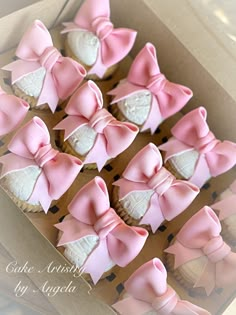 pink and white cupcakes in a box with bows on the top are ready to be eaten