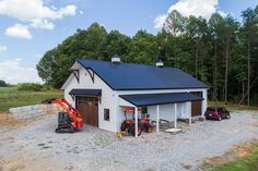 a garage with two cars parked in front of it and a tractor next to it