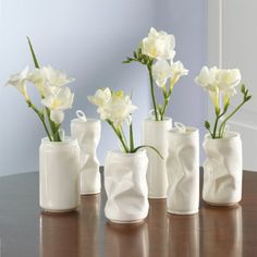 five white vases with flowers in them on a table