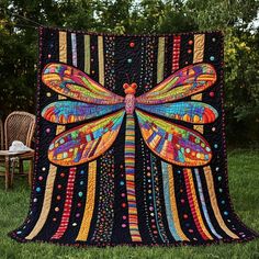 a colorful dragonfly quilt is on display in the grass