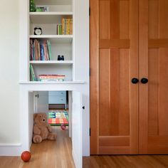 an open bookcase in the corner of a room with a stuffed animal on the floor