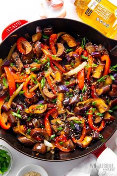 a pan filled with stir fry vegetables on top of a white table next to other dishes