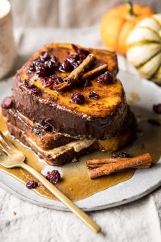 two slices of cake on a plate with cinnamon sticks and pumpkins in the background