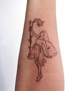 a small tattoo on the arm of a woman with a flower in her hand and a fairy holding an umbrella