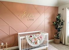 a baby's crib in front of a pink wall with the name ella lynn on it