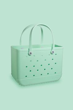 a green tote bag sitting on top of a green surface with holes in it