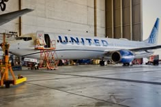 an airplane that is sitting on the tarmac in front of a building with workers around it