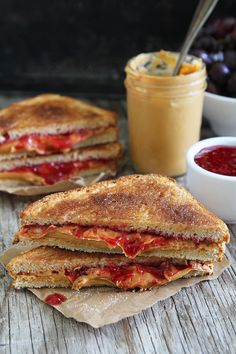 grilled cheese and tomato sandwich with condiments next to it on wooden table