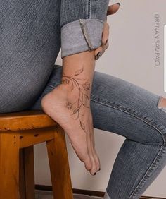 a woman sitting on top of a wooden stool with her legs crossed and tattooing