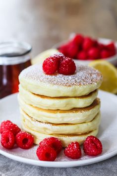 a stack of pancakes with raspberries and powdered sugar on the top are sitting on a white plate