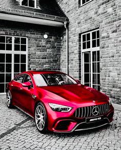 a red car parked in front of a brick building