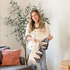 a woman standing in front of a couch holding a scarf