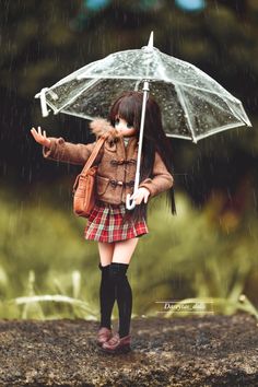 a doll is holding an umbrella in the rain