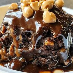 a piece of cake with chocolate frosting and nuts on top in a white bowl