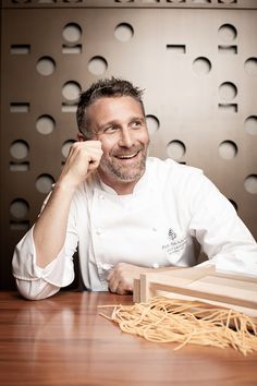 a man sitting at a table with some noodles in front of him and a wooden box on the table