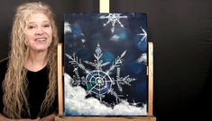 a woman standing next to an easel with snowflakes on it