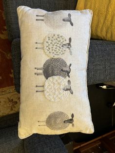 a pillow with sheep on it sitting on a chair in front of a blue couch