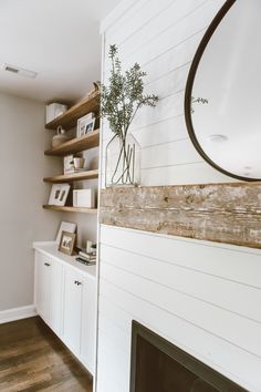 a living room with white walls and wooden shelves on either side of the fire place