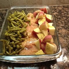 a glass casserole dish filled with potatoes, green beans and other food items