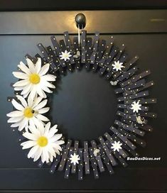 a wreath with white daisies hanging on the front door, decorated with black and gold strips