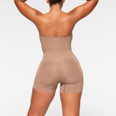 This strapless shortie solution is perfect for cinching your waist, holding in your tummy and core, and smoothing your thighs under mini skirts and dresses. Features pique stitching that supports your bust, an open gusset, and removable adjustable straps that you can wear as shoulder straps, cross back, or as a halter. | SKIMS Strapless Shortie Bodysuit | Medium Neutral | Seamless Sculpt Fitted Shorts With Built-in Bra, Mid-thigh Length, Beige Shapewear With Built-in Bra, Short Length, Stretch Full Coverage Shapewear Corset, Sculpting Shapewear With Built-in Bra, Short Length, Sculpting Shapewear With Built-in Bra In Short Length, Seamless Sculpting Strapless Shapewear, Fitted Tube Top With Built-in Bra Shapewear, Stretch Smoothing Bandeau Shapewear, Strapless Shaping Bodysuit Shapewear