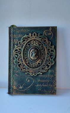 a book with an ornate design on the front and back cover is sitting on a white surface