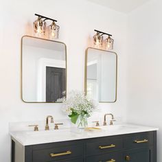 two mirrors are above the double sink vanity in this white and black bathroom with gold trim