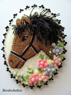 a brown horse with flowers on it's head is hanging from a white wall