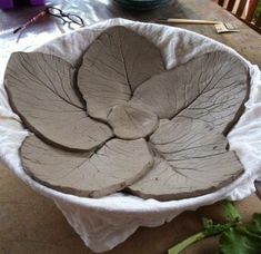 a bowl that is made out of clay and has leaves on the inside of it