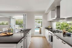 a large kitchen with white cabinets and black counter tops, along with an open door leading to the pool