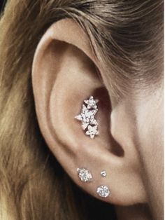 a close up of a person's ear with three diamond studs on it