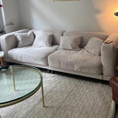 a living room filled with furniture and a glass coffee table on top of a rug