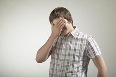 a young man covers his eyes with his hands