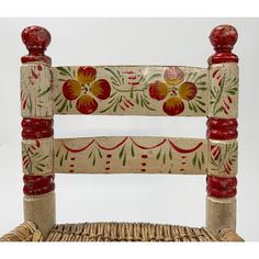 a wooden chair with red and yellow flowers painted on it's backrests