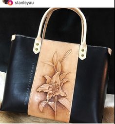 a black and brown bag with a flower painted on it