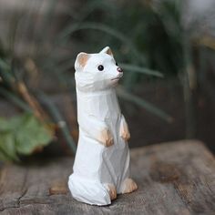 a small white cat figurine sitting on top of a wooden table