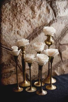 a group of white roses sitting on top of gold vases