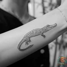 a black and white photo of a woman's arm with an alligator tattoo on it