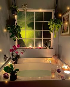 a bathtub filled with candles and flowers next to a window covered in greenery