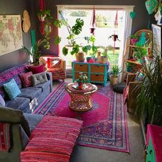 a living room filled with lots of colorful furniture and plants on top of the couches