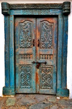 an old wooden door with ornate carvings on the front and side doors are painted blue