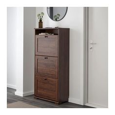 a tall wooden cabinet with three drawers in front of a mirror on the wall next to a door