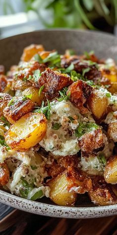 a bowl filled with potatoes and meat covered in sauce on top of a wooden table